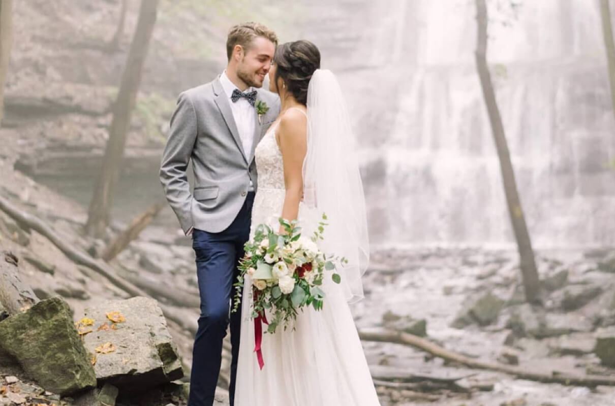 Bride and groom about to kiss in front of waterfall