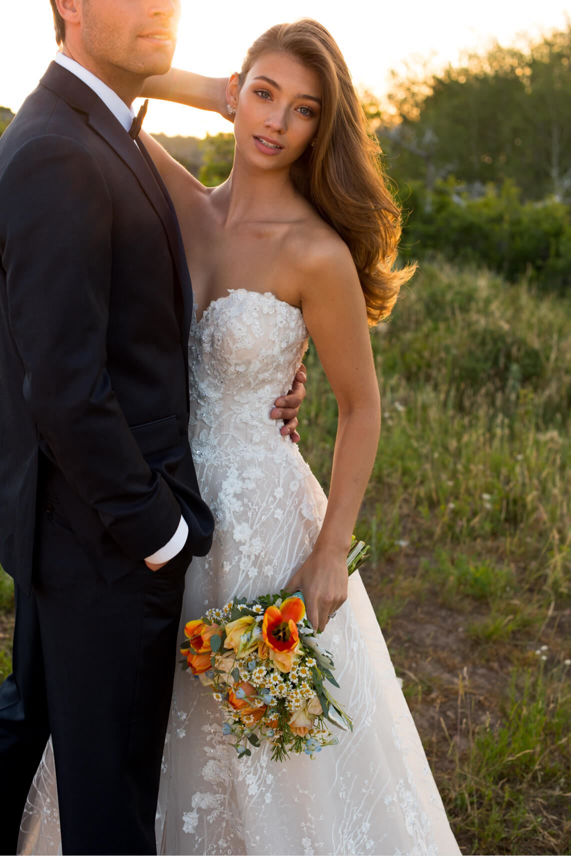 Brunette bride and groom standing together in field