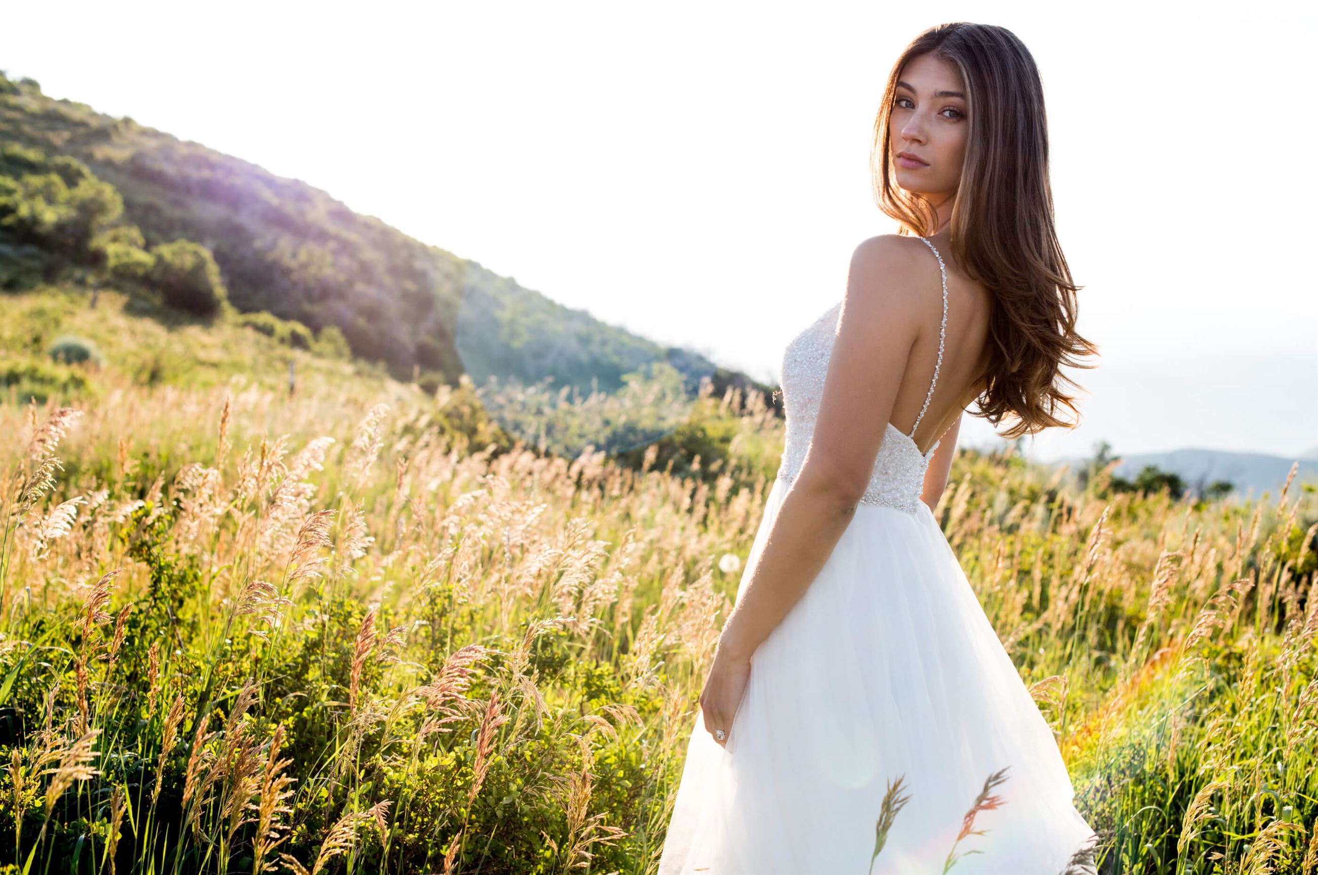 Brunette bride wearing white wedding dress in field