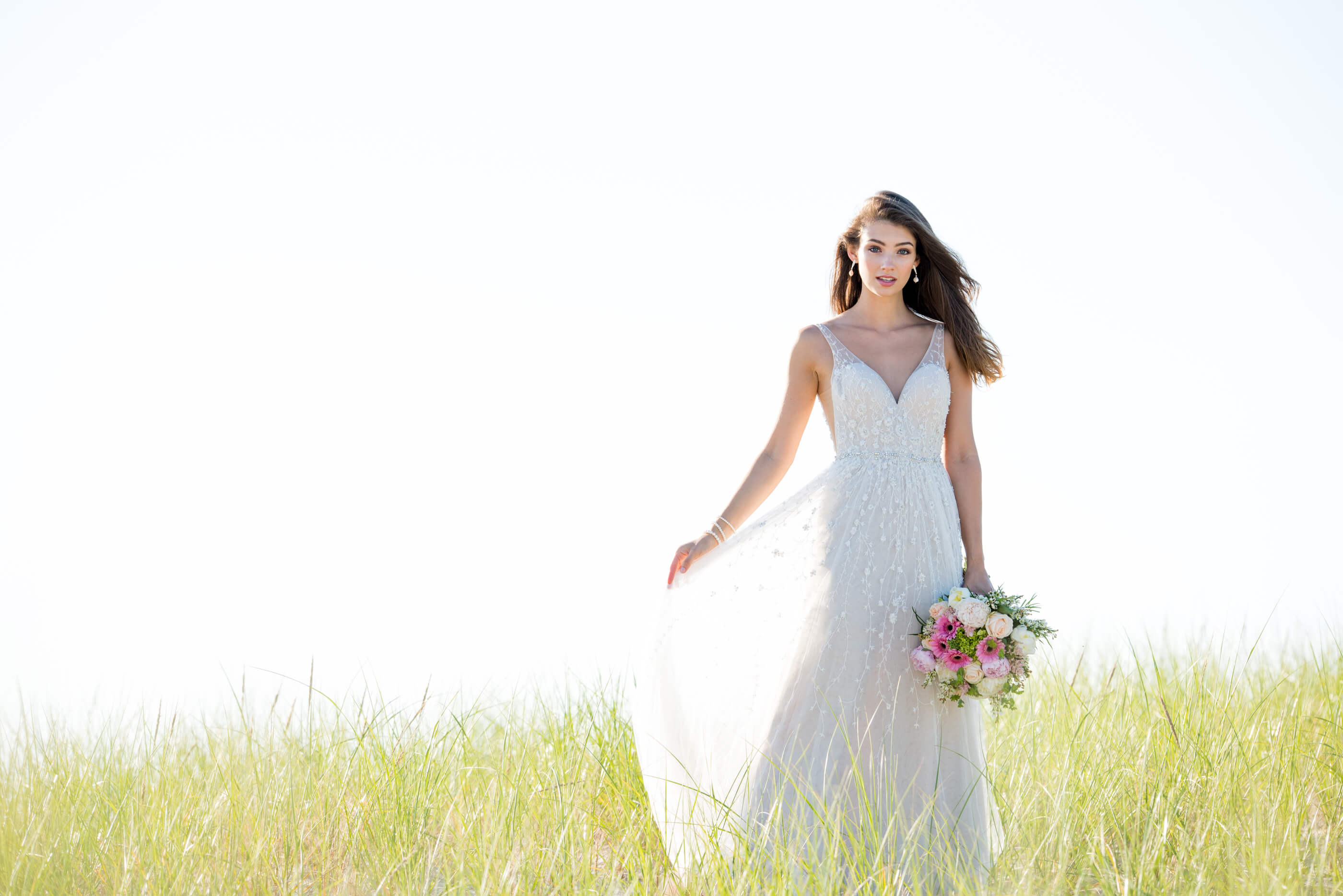 Brunette bride holding bouquet in field